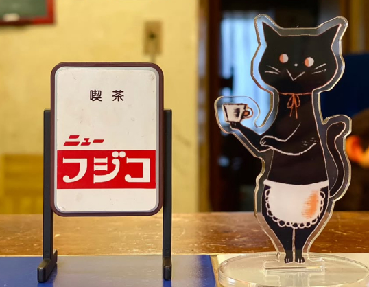 お店の看板と黒猫の写真